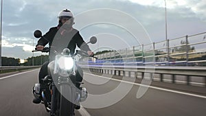 Man riding scrambler motorbike on the highway with lights turned on, front view