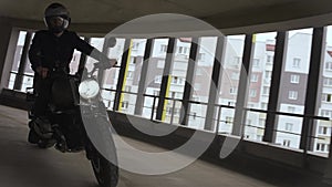 Man is riding a scrambler motorbike on top of the multi-level parking in city