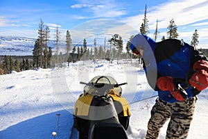 Man riding snomobile in the mountains near cabin houses and trees