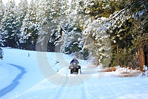 Man riding snowmobile or fourwheeler on the country side trail near water canal