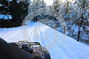 Man riding snowmobile or fourwheeler on the country side trail near water canal