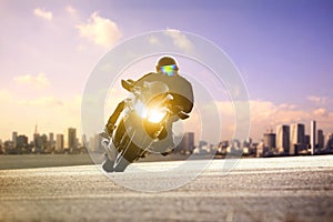 Man riding sport motorcycle lean on curve road against urban skyline background