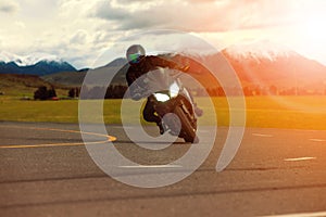 man riding sport motorcycle leaning in sharp curve with traveling scene background