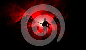 Man with riffle at spooky forest at night. Strange silhouette of hunter in a dark spooky forest at night, mystical landscape surre