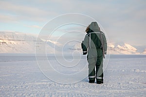 Man with a rifle looks out on the horizon in arctic landscape at Svalbard