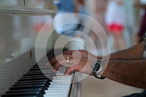Man with a ring on his finger and a watch on his wrist plays piano