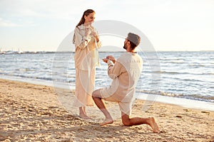 man with ring making proposal to woman on beach