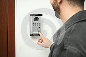 Man ringing intercom with camera in entryway, closeup