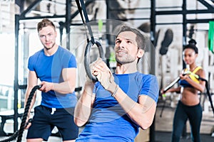 Man at rings doing fitness exercise in gym