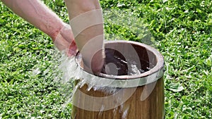 Man rinses out a new oak wood tub with hands and clear water