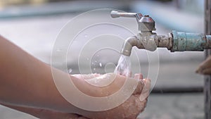 Man Rinsing Hands by old faucet with water leaking