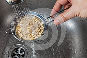 Man rinsing raw quinoa seeds