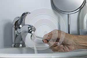 The man rinsing shaving razor under tap water