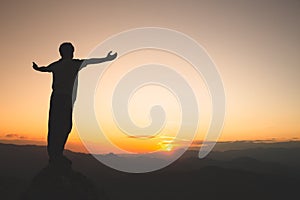 Man rise hand up on top of mountain and sunset,  Freedom and travel adventure concept. Religious beliefs, Copy space