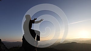 man rise hand up on top of mountain and sunset sky abstract background. Freedom and travel adventure concept. Pray or Praying,