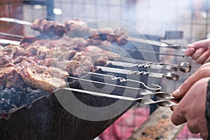 a man roasts meat on a fire. Close-up of hands and barbecue.