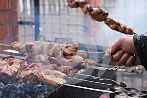 a man roasts meat on a fire. Close-up of hands and barbecue.