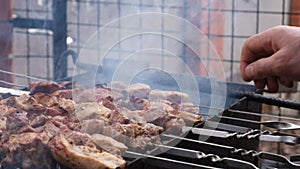 a man roasts meat on a fire. Close-up of hands and barbecue.