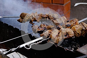 a man roasts meat on a fire. Close-up of hands and shish kebab. Cooking pork neck on the grill. Roasted carrots.