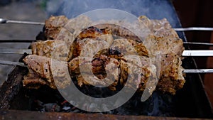 a man roasts meat on a fire. Close-up of hands and shish kebab. Cooking pork neck on the grill. Roasted carrots.