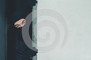 Man robber,Thief in mask hiding behind a empty wall with space for text