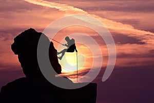 Man rock climber silhouette over bright sunset