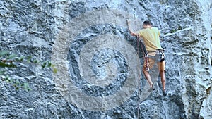 Man rock climber starting to climb on a cliff, searching, reaching and gripping hold.