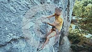 Man rock climber starting to climb on a cliff, searching, reaching and gripping hold.