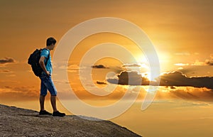 Man is on rock & enjoying sunset above earth.