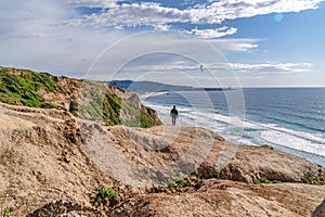 Man on rocky mountain bordering the shoreline of ocean in San Diego California