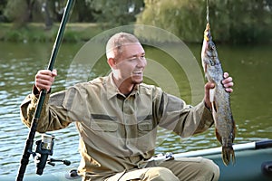 Man with rod and catch fishing from boat