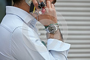Man with Rolex Submariner watch during a phone call before Emporio Armani fashion show, Milan Fashion Week street
