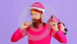 Man with roller skates and protective helmet. Bearded male with skating rollers eating lollipop.