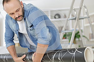 man rolling carpet at home