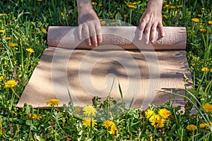 Man rolling her mat after a yoga class on a green meadow on a summer sunny day