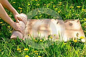 Man rolling her mat after a yoga class on a green meadow on a summer sunny day