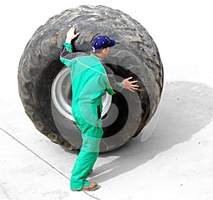 Man rolling huge truck wheel