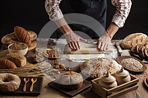 Man rolling out dough on kitchen table, close up