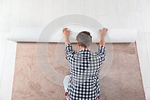 Man rolling out new carpet flooring indoors