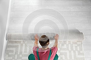 Man rolling out new carpet flooring indoors, top view.