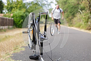 Man rolling wheel towards broken down bicycle