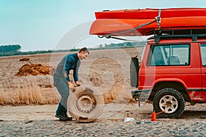 Man rolls a new replacement wheel to 4x4 off road truck