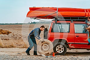 Man rolls a new replacement wheel to 4x4 off road truck