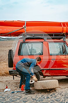 Man rolls a new replacement wheel to 4x4 off road truck