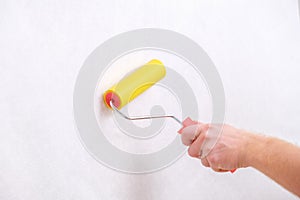 A man rolls out a canvas of white wallpaper with a suture yellow roller. Removing air bubbles and glue. Wallpapering.