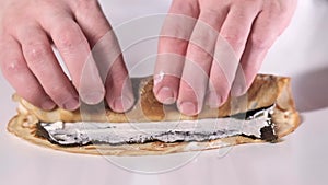 Man rolls a pancake with a filling. Asian food. Fast food in a restaurant.