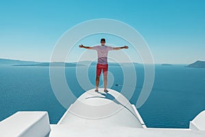 Man on the roof enjoying view of Santorini island and Caldera in Aegean sea. Greece