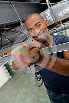 Man in roof space holding cable forward