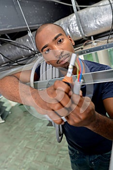 Man in roof space holding cables and tester