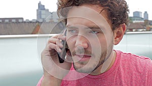 Man On Roof Terrace Using Digital Tablet And Mobile Phone